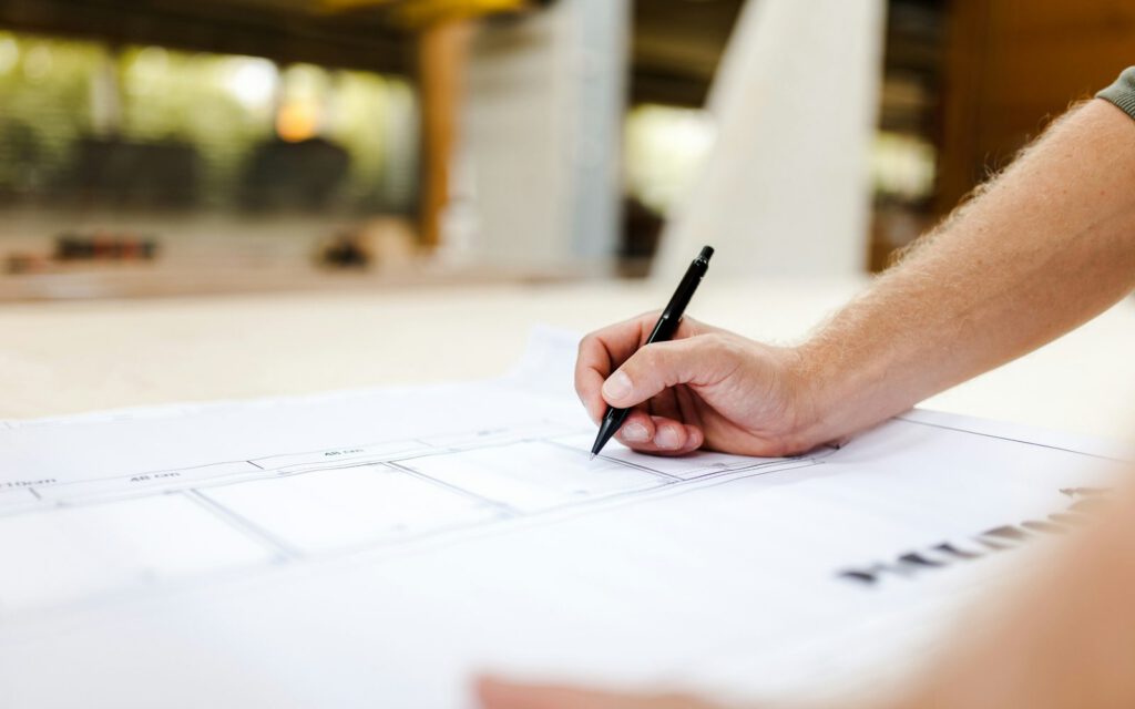 Hand zeichnet einen Grundriss auf Papier